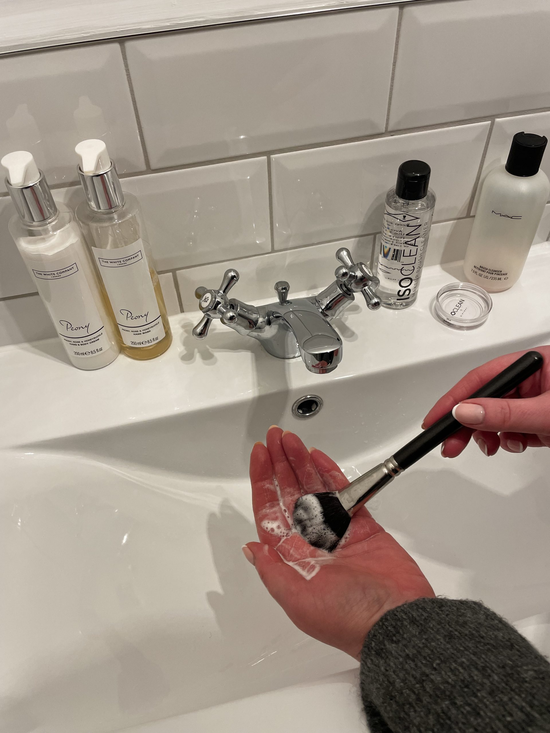 cleaning makeup brush at sink