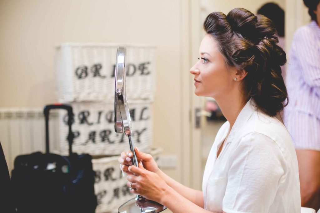 Bride looks at makeup in hand-held mirror